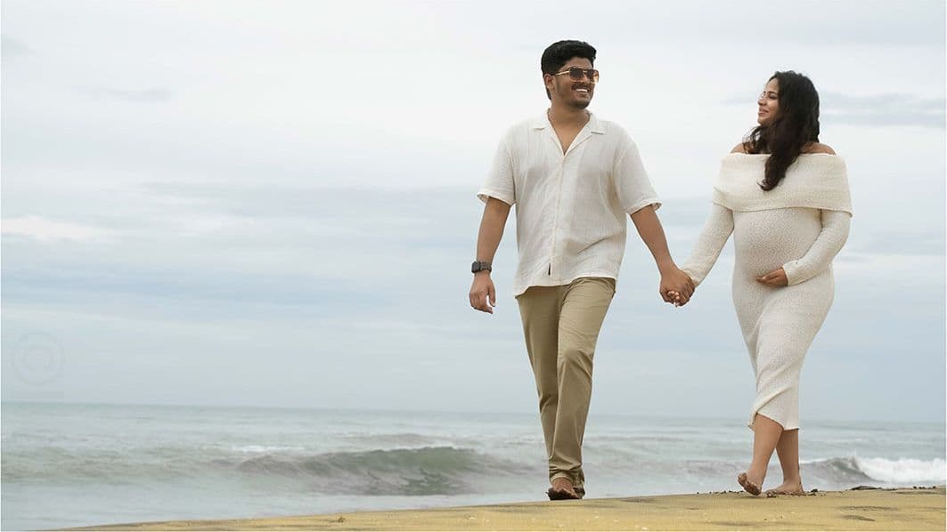 Couple walking hand in hand along the beach at golden hour