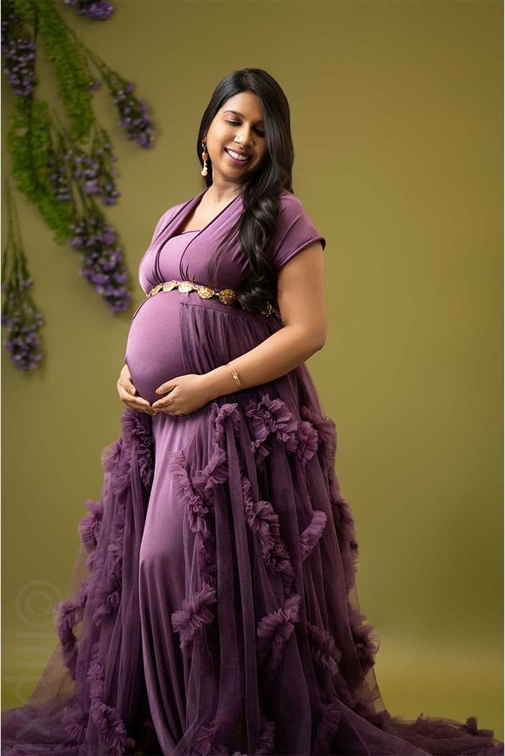 Maternity portrait in a purple gown against a floral backdrop