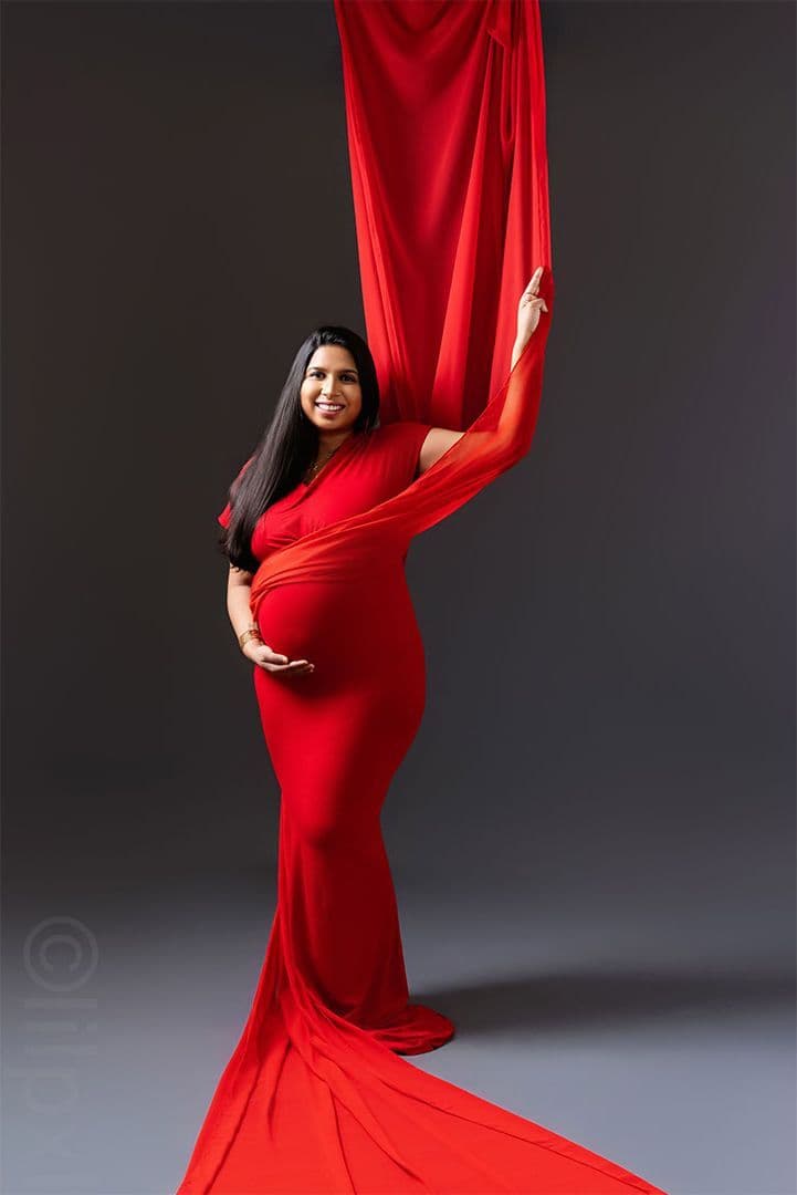 Maternity portrait draped in flowing crimson fabric